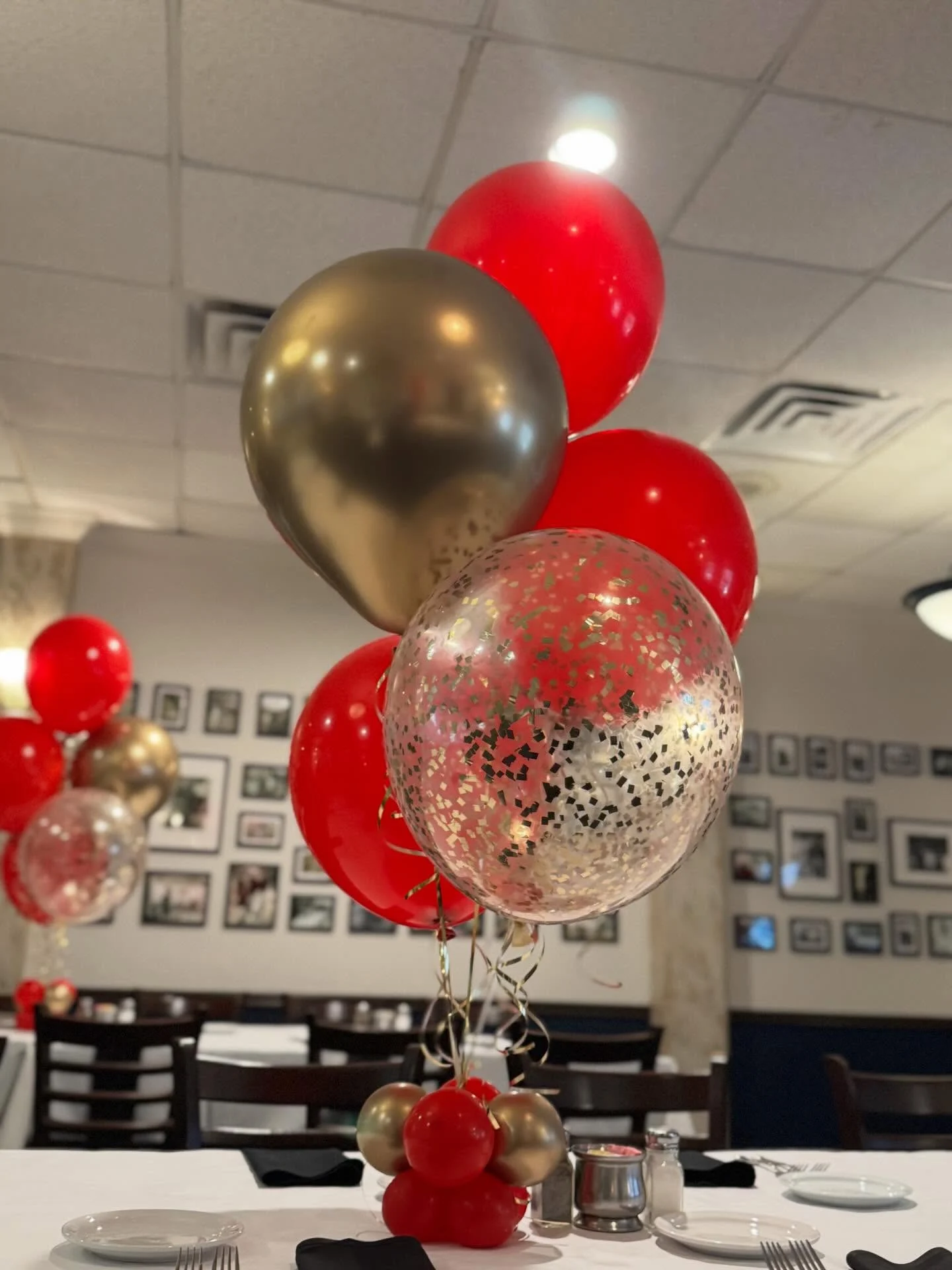 Red, gold and clear confetti balloons arranged above a dining table.