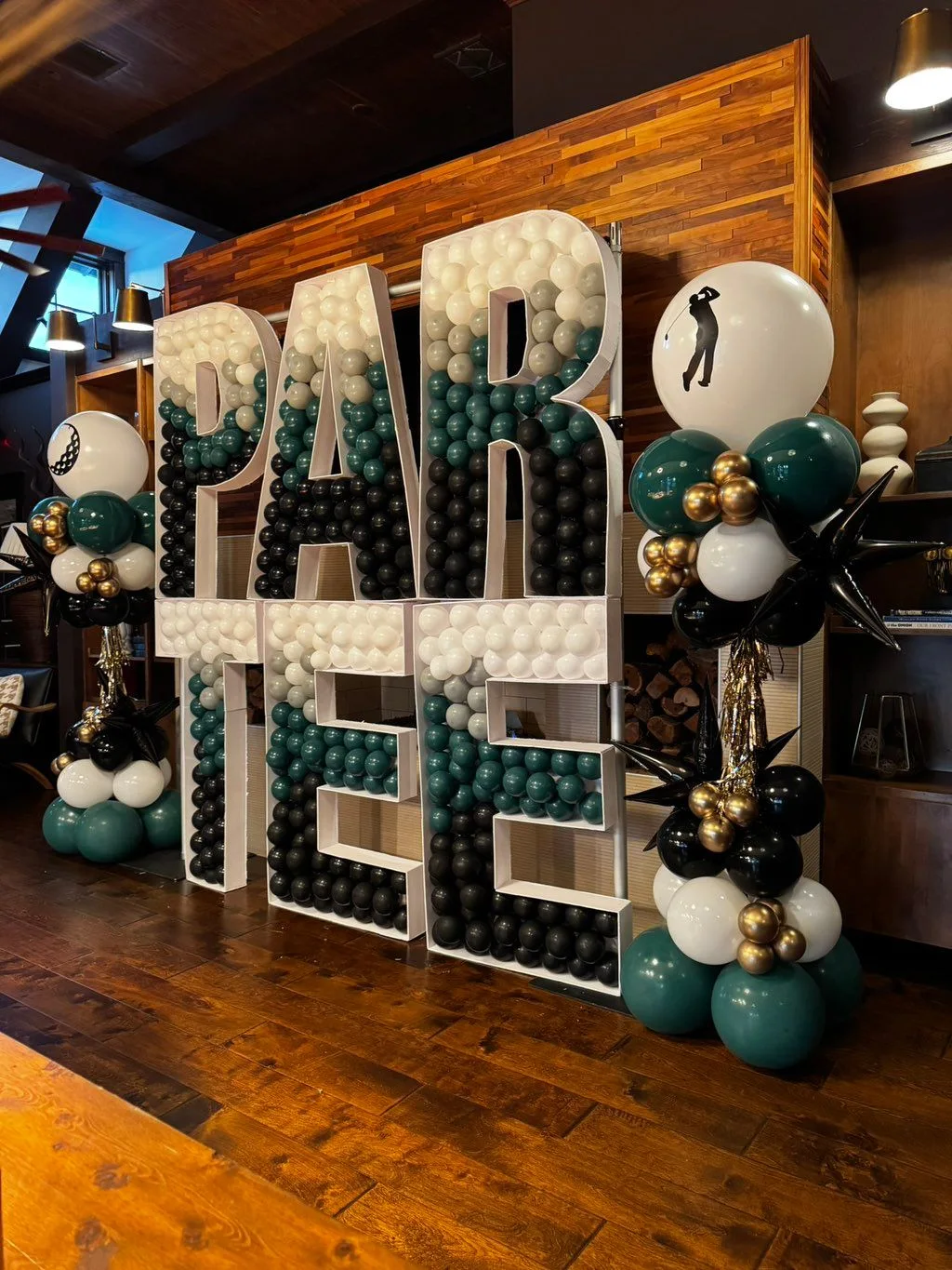 Forest green, white and gold balloons surround a golf-themed PAR TEE display.
